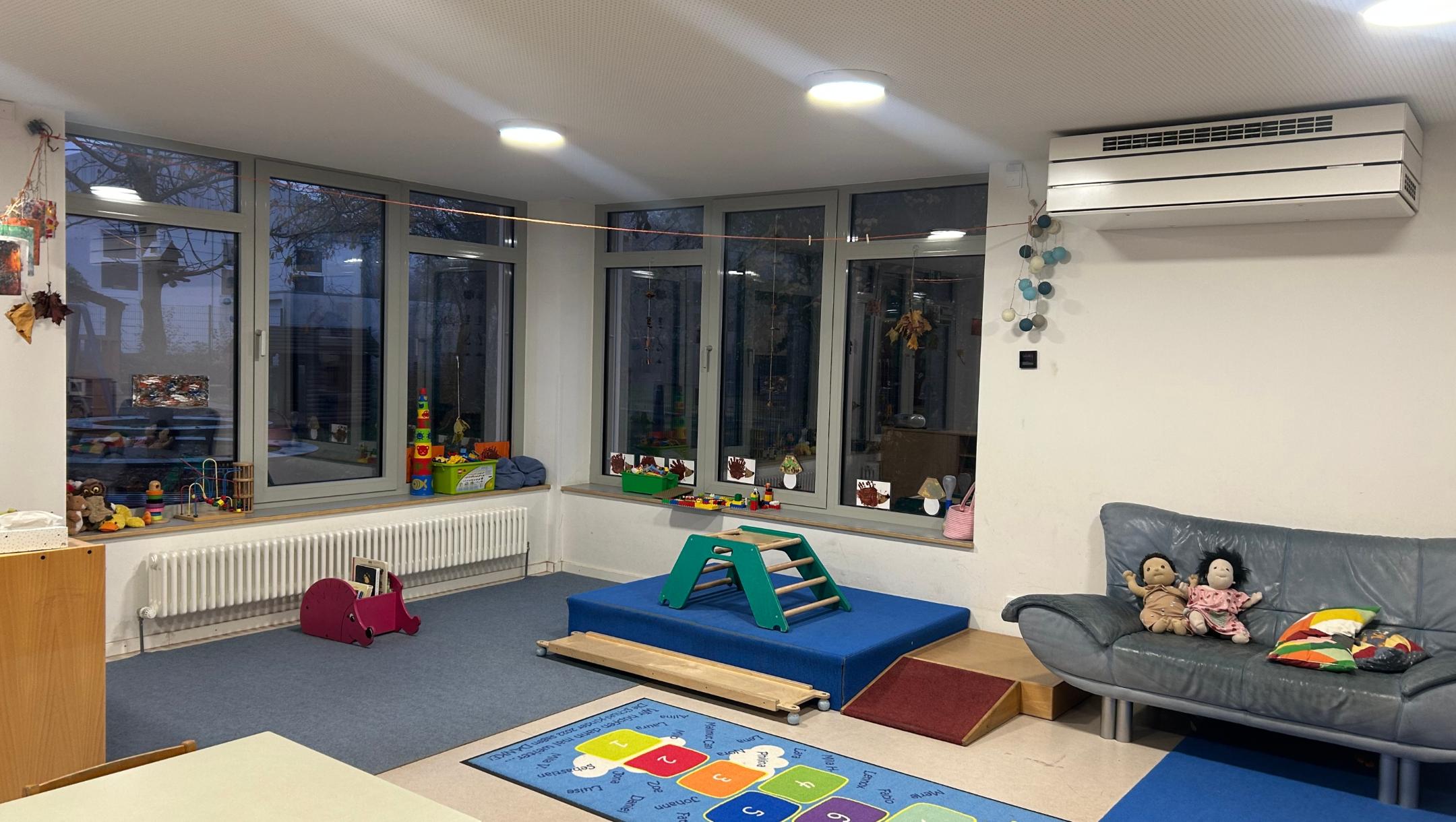 Man sieht einen Spielraum der KiTa mit Hüpfkästchen und Kletterecke