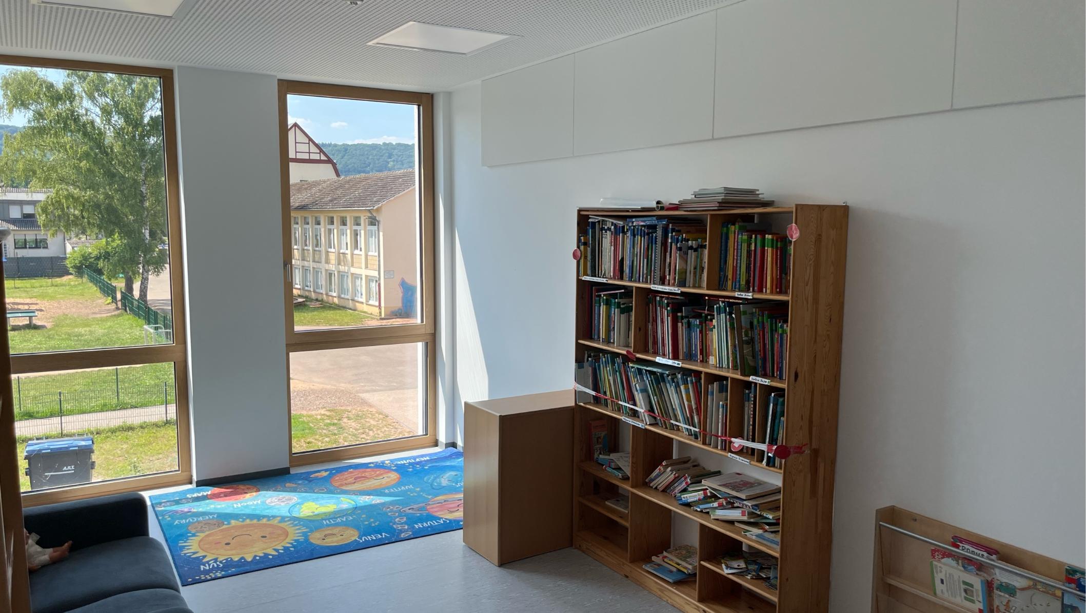 Man sieht die Bibliothek mit einem Regal mit Büchern und einer Lese-Couch
