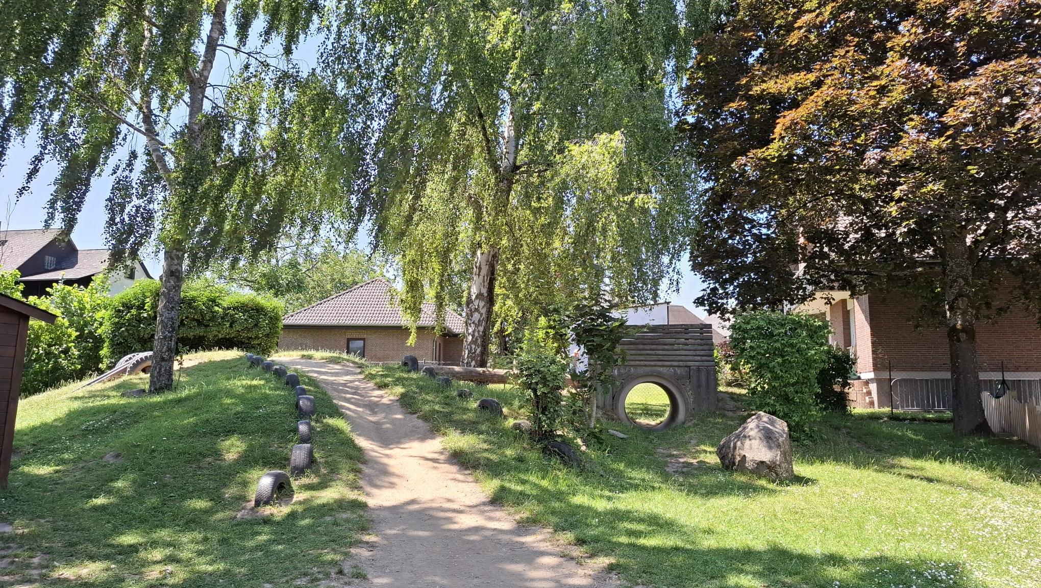 Man sieht einen Tunnel, sowie Reifen zum balancieren auf dem Spielplatz der Kita (c) Katholische KiTa gGmbH Trier Man sieht einen Tunnel, sowie Reifen zum balancieren auf dem Spielplatz der Kita
