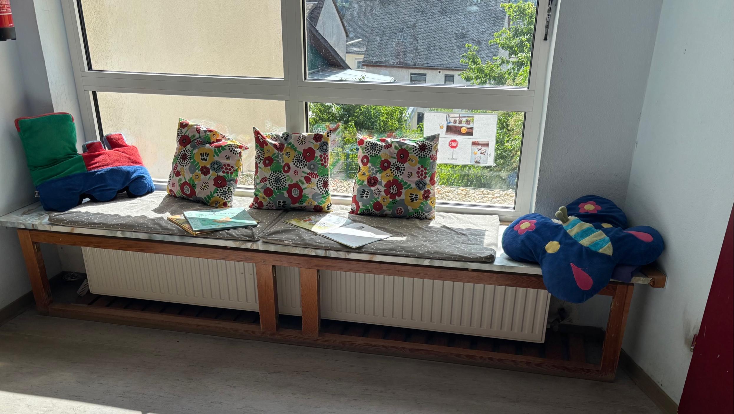 Man sieht ein Fenster mit einer installierten Bank mit Kissen