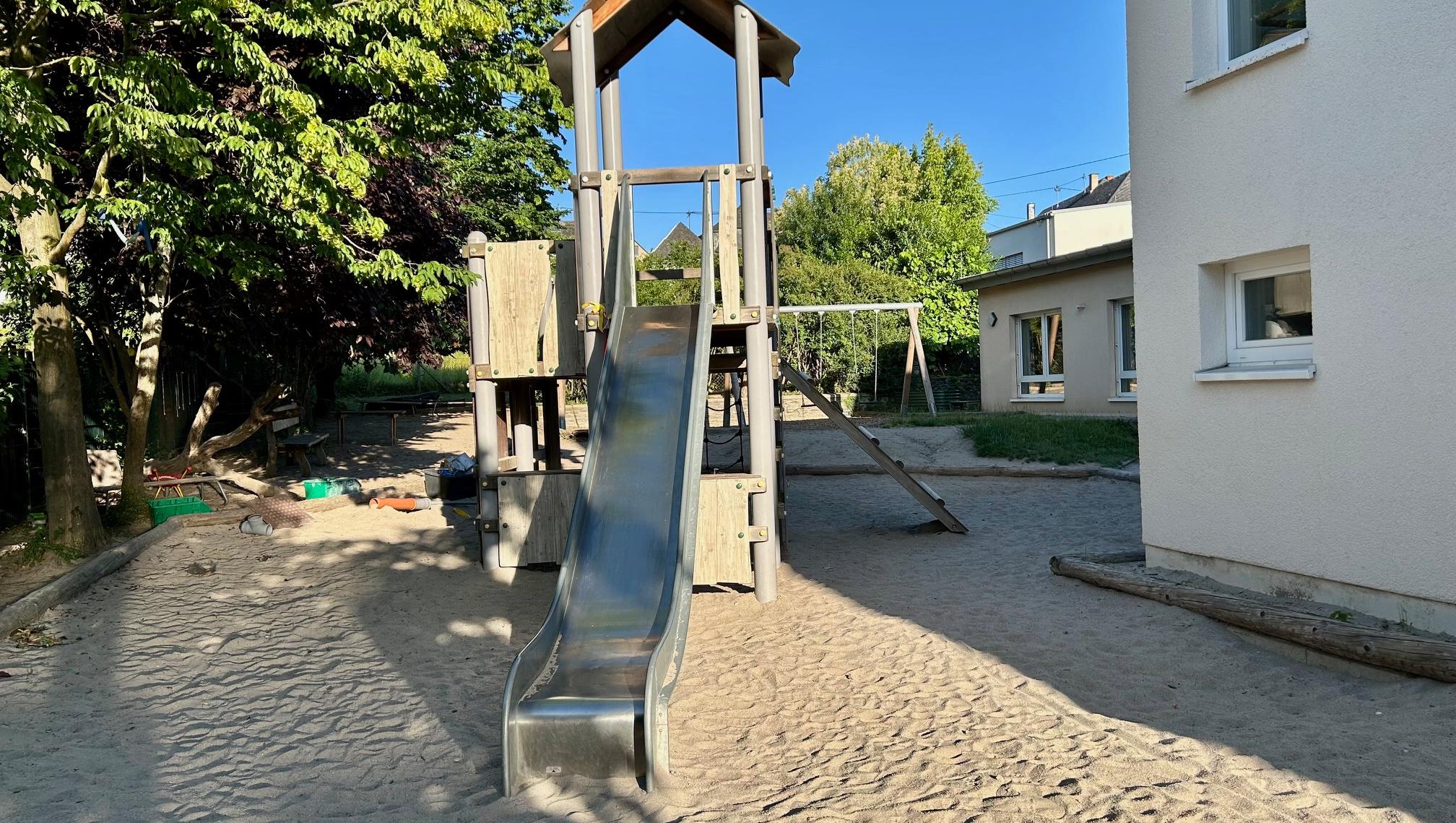 Man sieht den Rutschturm und Sandkasten der KiTa
