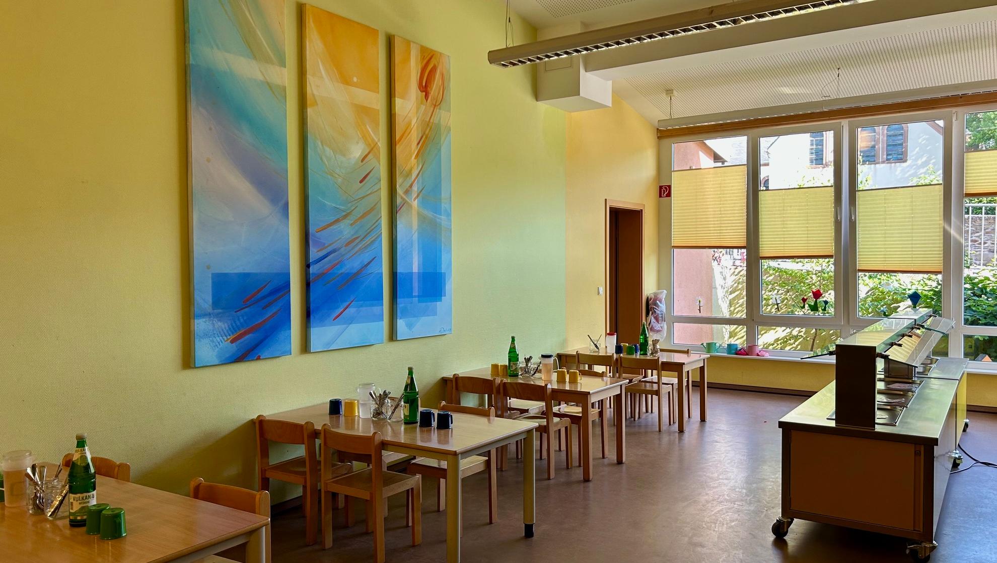 Man sieht das Bistro der Kita mit kleinen Tischen und Stühlen