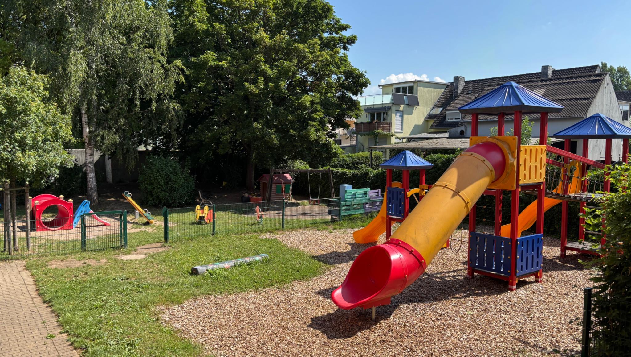 Man sieht den Spielplatz mit der bunten Rutsche