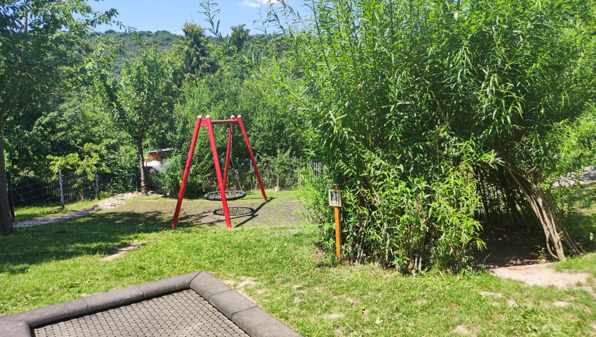 Man sieht Trampolin und Schaukel im Außenbereich