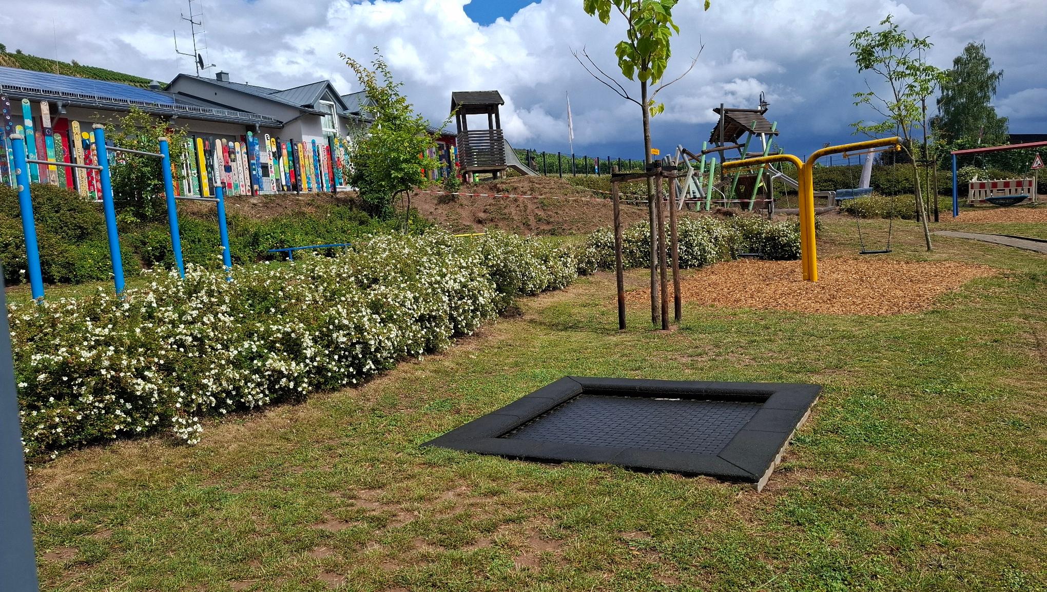 Man sieht den Außenbereich der KiTa mit einem Trampolin