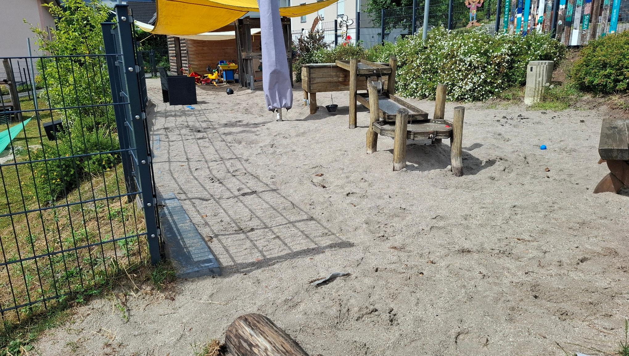 Man sieht den Außenbereich und den Sandkasten der Kita