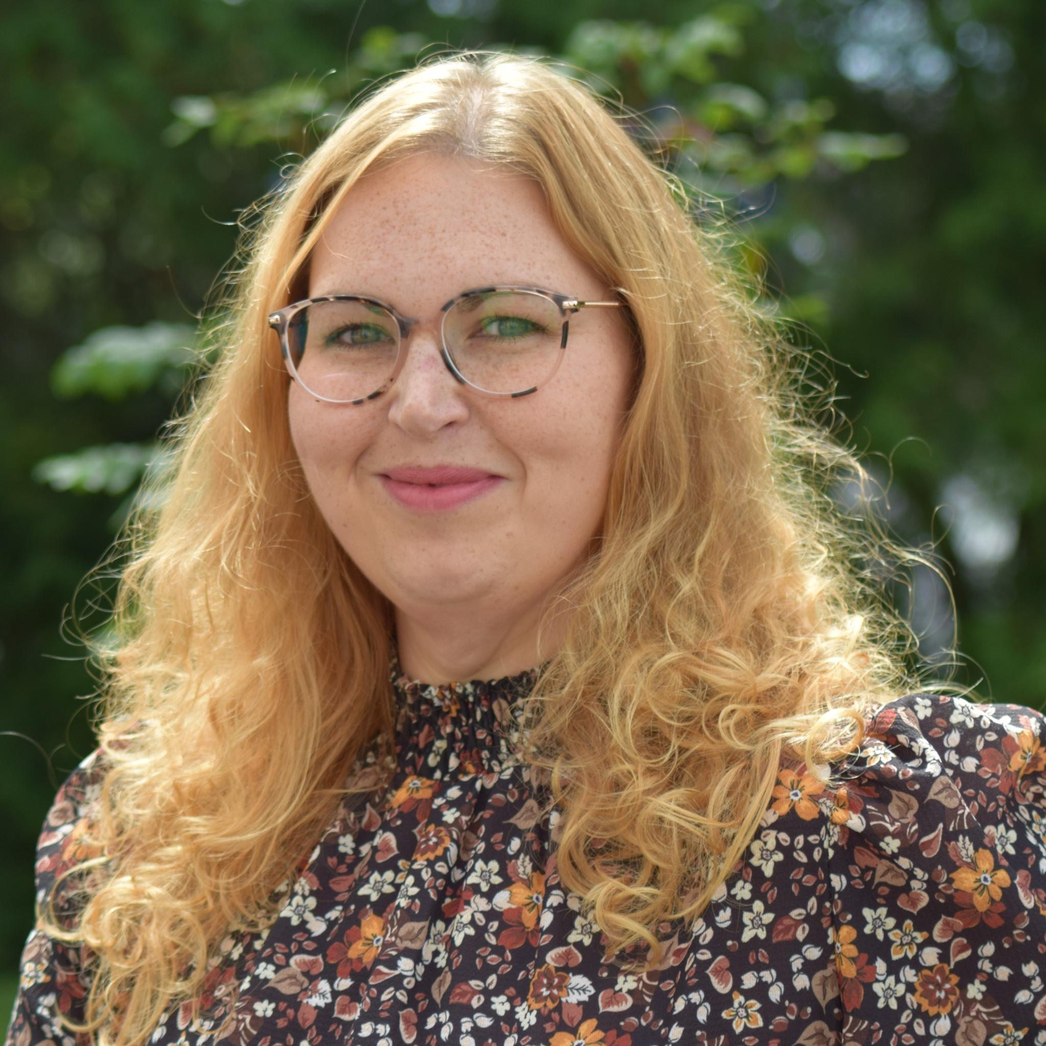 Man sieht ein Portraitfoto von Frau Prüm vor grünem Hintergrund